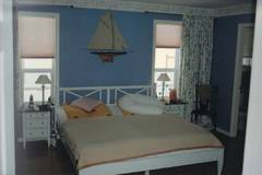 Eines der relativ groen Schlafzimmer mit hohen Fenstern.  Die Tr rechts im Bild fhrt zu einem Badezimmer.