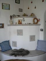 Der Kachelofen hat in jedem Zimmer einen anderen Stil und doch ergibt er ein harmonisches Ganzes. Im Eßzimmer ist er ein verputzter runder Ofen auf 2 Ebenen plus gemauerter Sitzbank mit eingesetzten handbemalten Kacheln.