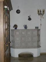 Im Flur wird der verbleibende Rest der Heizwrme in einem einfachen aber geflligen Ofen genutzt.  Hier gibt es bei platzsparendem Design nur eine Hhenebene, aber 6 Lichtebenen.  In allen Zimmern pat der Kachelofen gut zu den im Brstenputz gehaltenen Wnden.