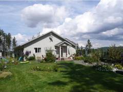 Die sdwestliiche Giebelseite. Links am Bildrand die Spielgerte, sonst berall Rasen und mit vielen Inseln aus Blumen.  Selbst an dieser Rckseite des Gebudes gibt es architektonische Akzente.